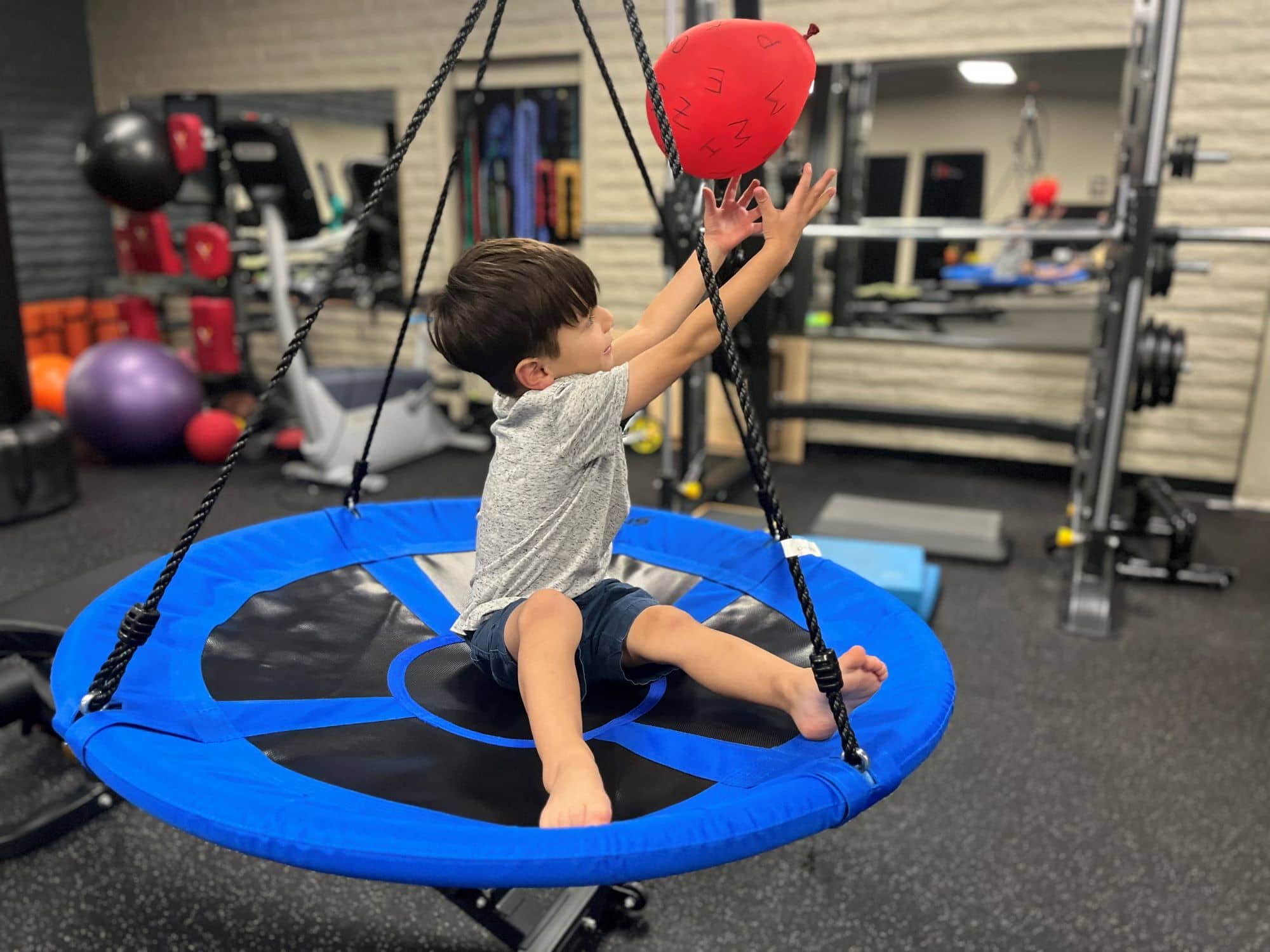 child playing with a balloon in a suspended matt